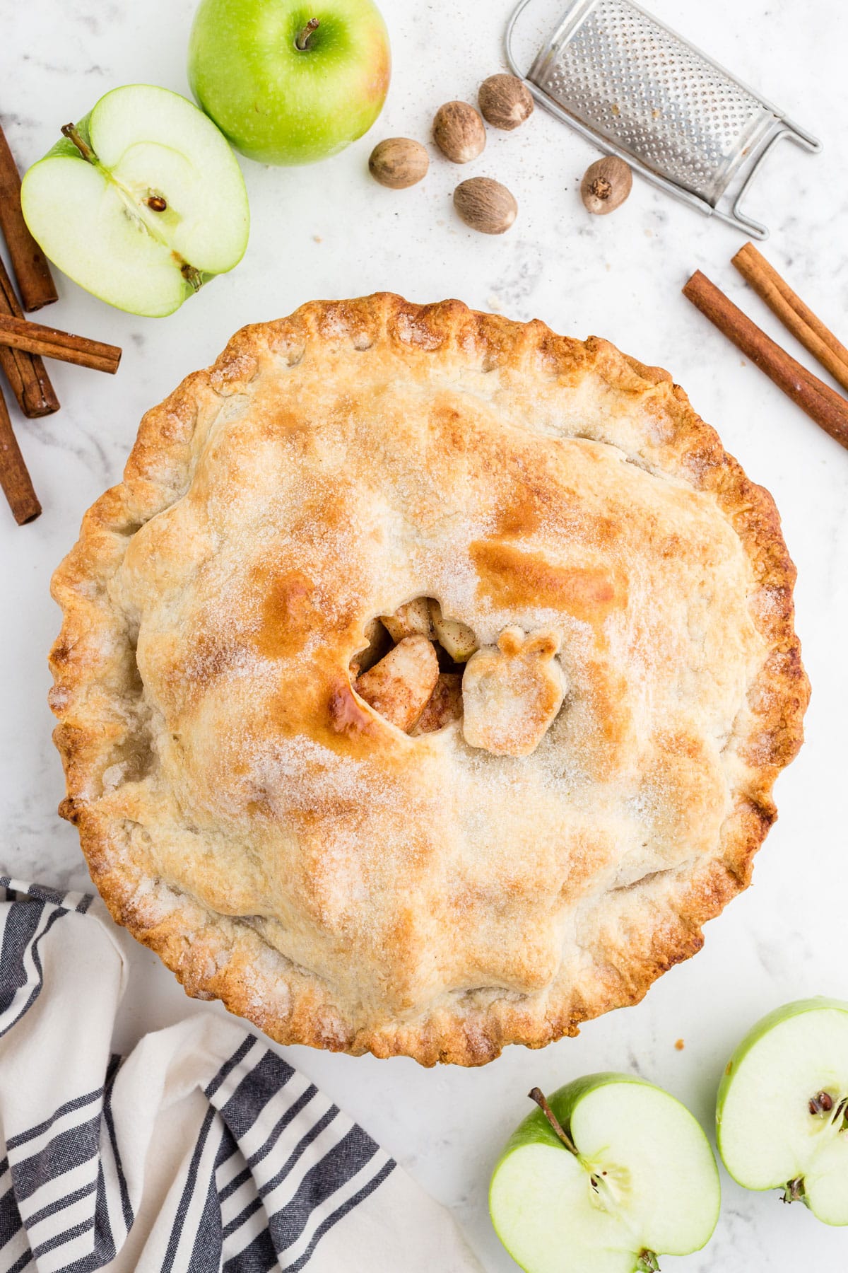 top of an apple pie featuring an apple cutout and sugar sprinkled butter pie crust