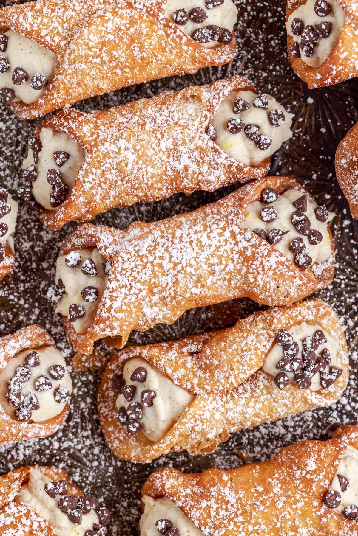cannoli dusted with powdered sugar and mini chocolate chips on a baking sheet