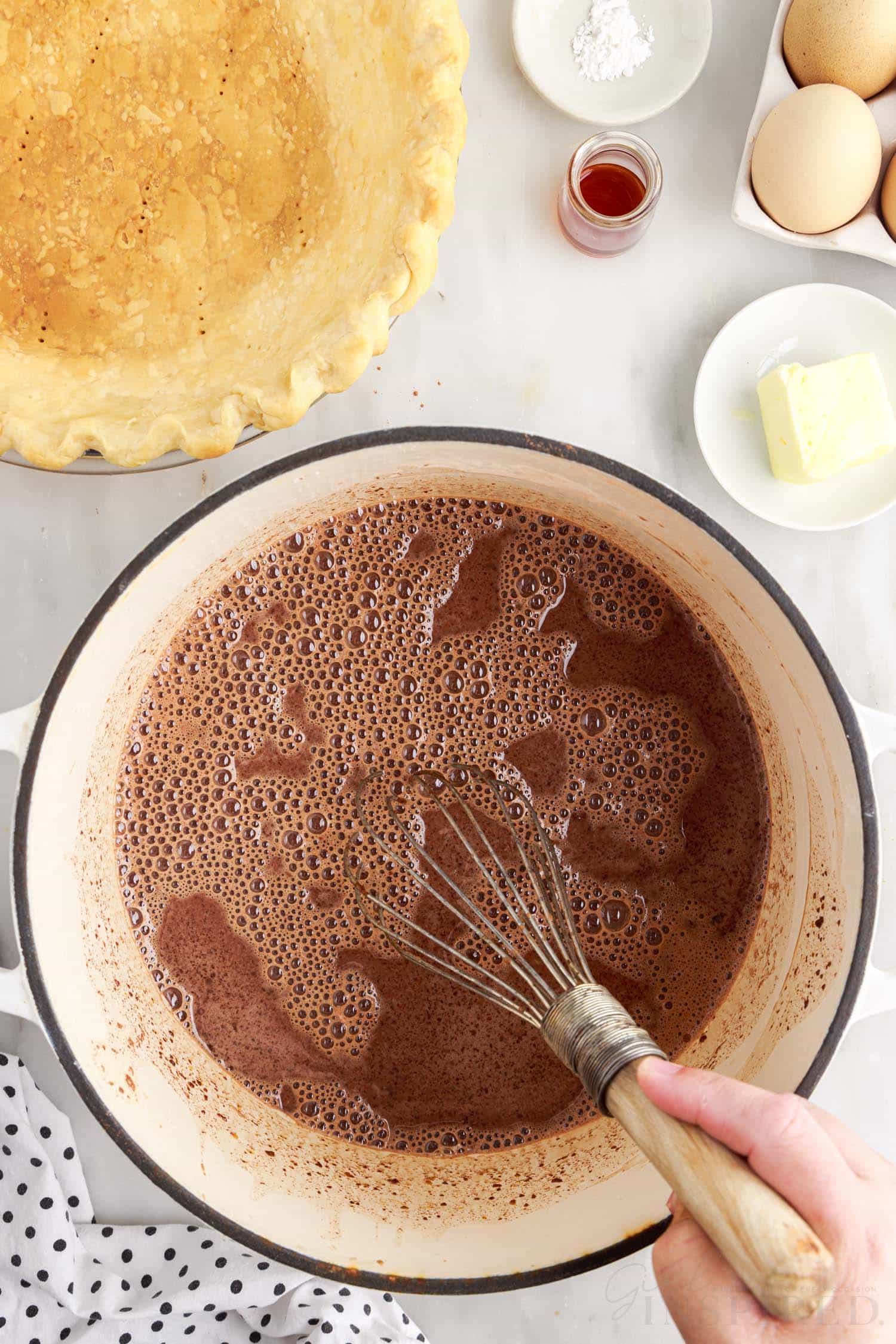 a bowl filled with chocolate pie filling being whisked