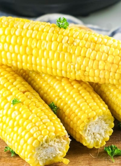 Instant pot corn on the cob stacked on a cutting board.