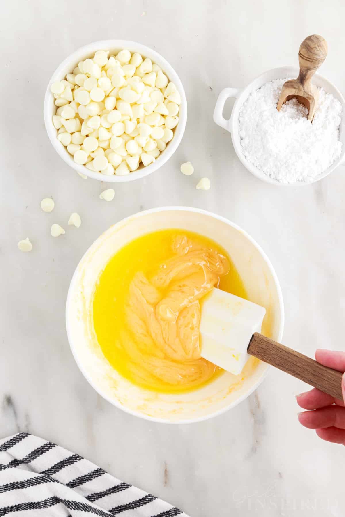 Butter and melted orange chocolate mixture being stirred with a spatula.