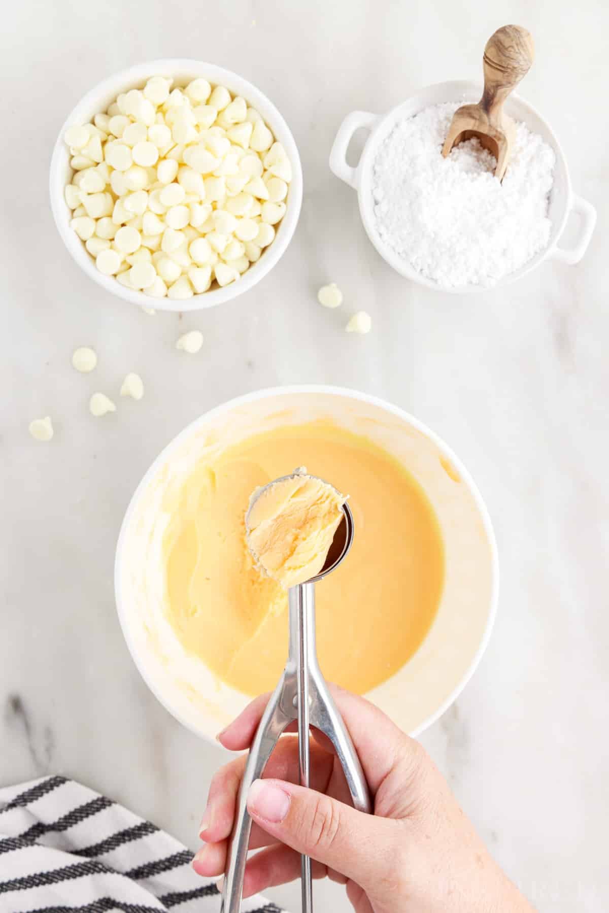 Cookie scoop dipped into bowl of orange creamsicle truffle mixture.