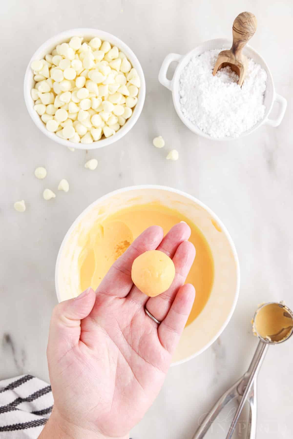 Orange creamsicle truffle ball in palm of hand.