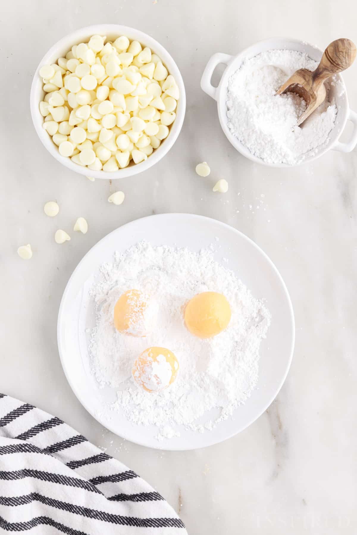 Orange creamsicle truffle balls rolled in plate with powdered sugar.