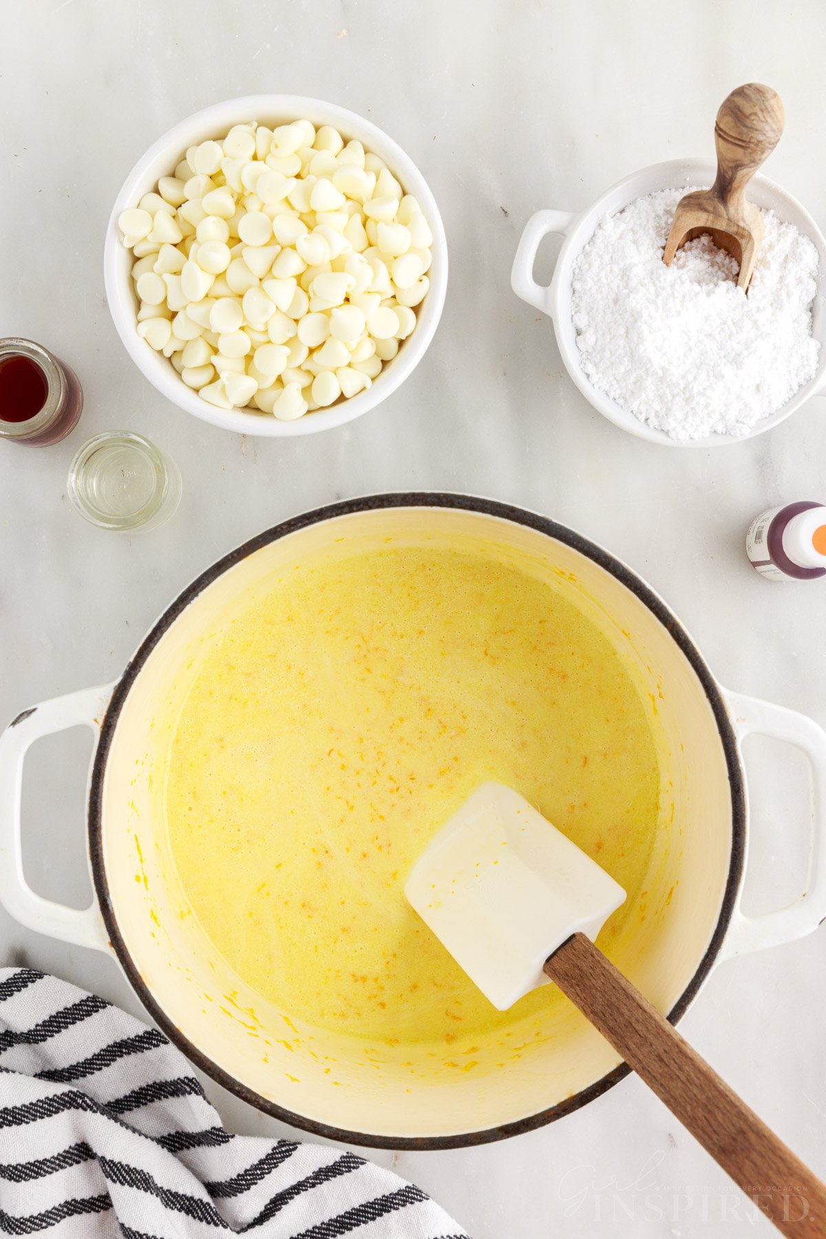 Melted butter, orange zest, and cream mixture in a saucepan with spatula.