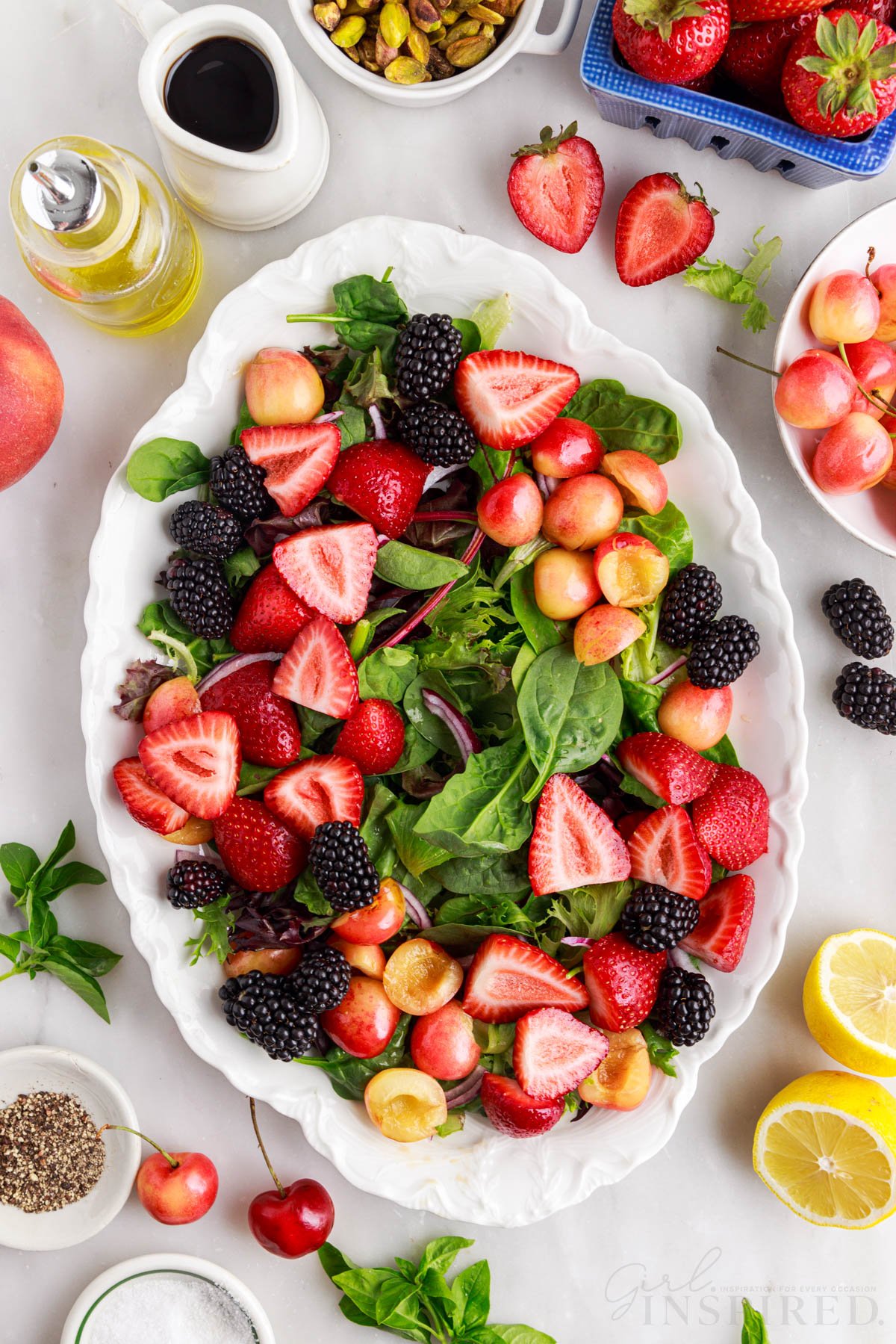 Berries arranged in groups of same color on the bed of greens to build Peach Burrata Salad.