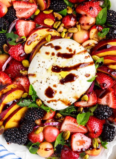Peach Burrata Salad with berries, pistachios, and cherries drizzled with a vinaigrette