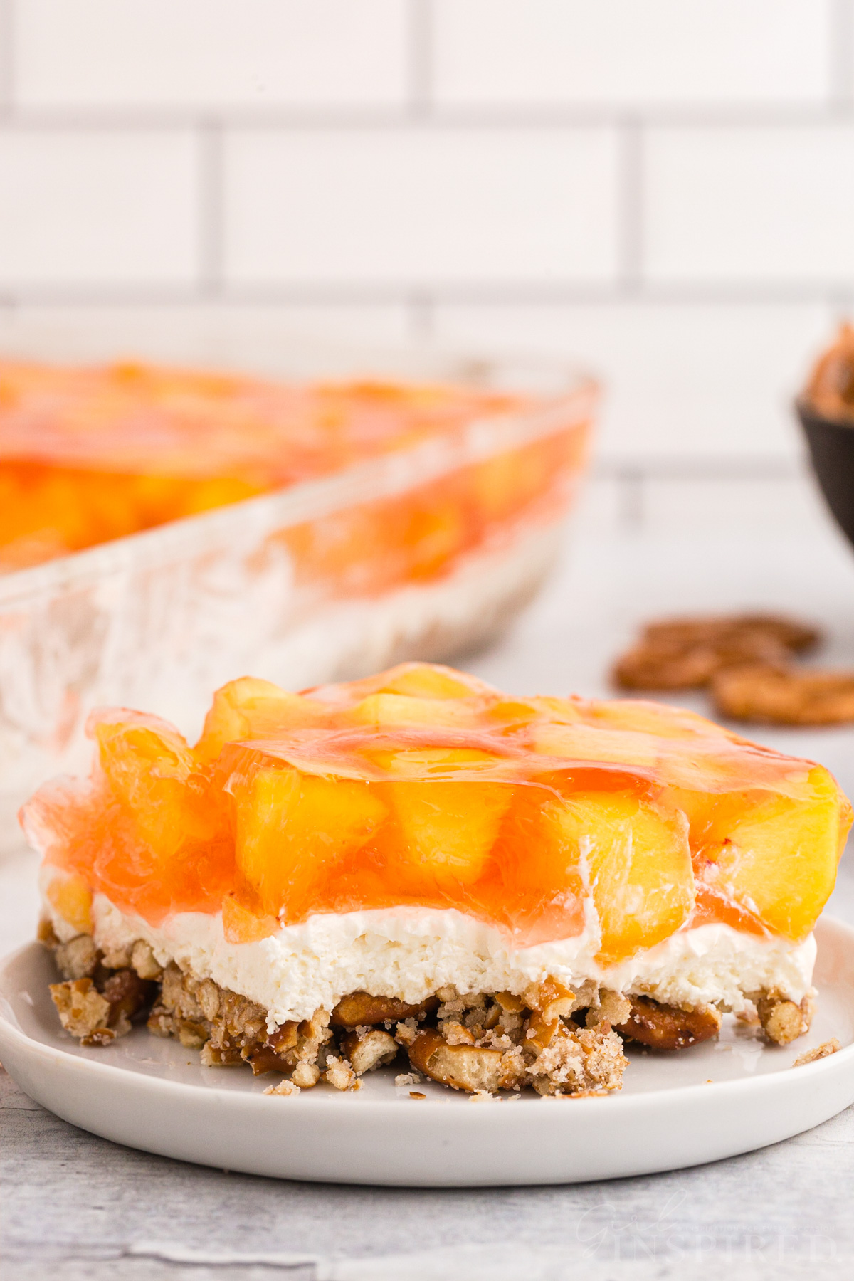 Slice of peach pretzel salad on a white place, on top of a marble countertop