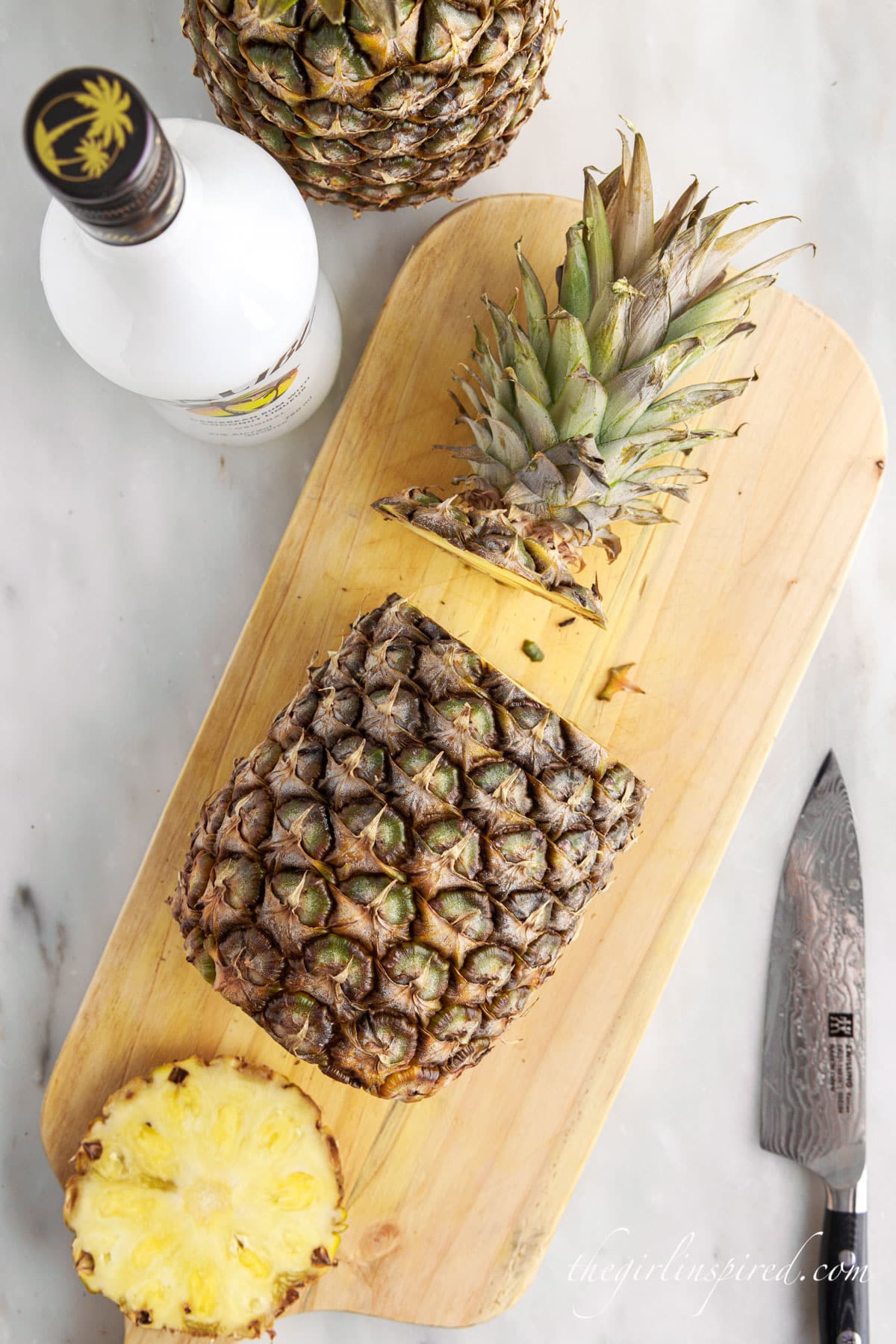 pineapple with top and bottom cut off on cutting board.