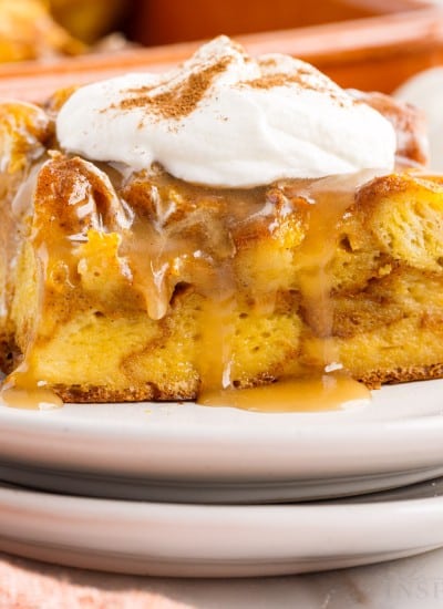 close up of a slice of pumpkin bread on a plate with caramel sauce and whipped cream on top