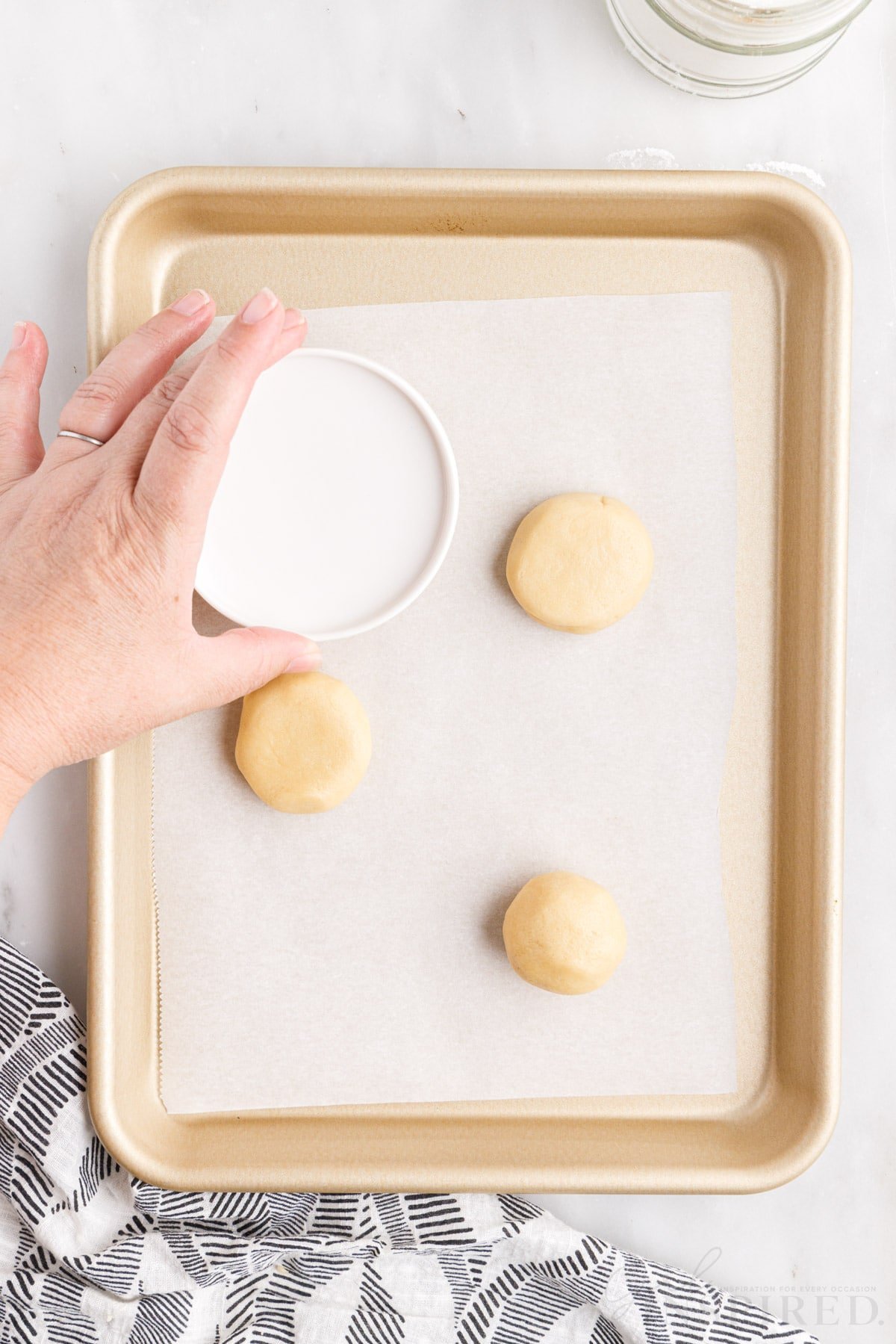 using the bottom of a ramekin to flatten the sugar cookie dough balls