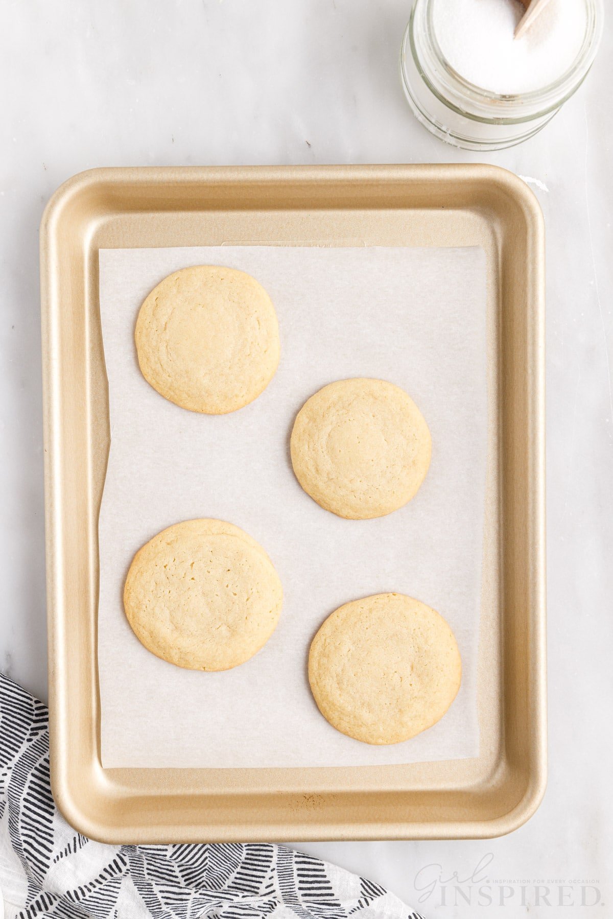 four soft baked sugar cookies on the baking sheet