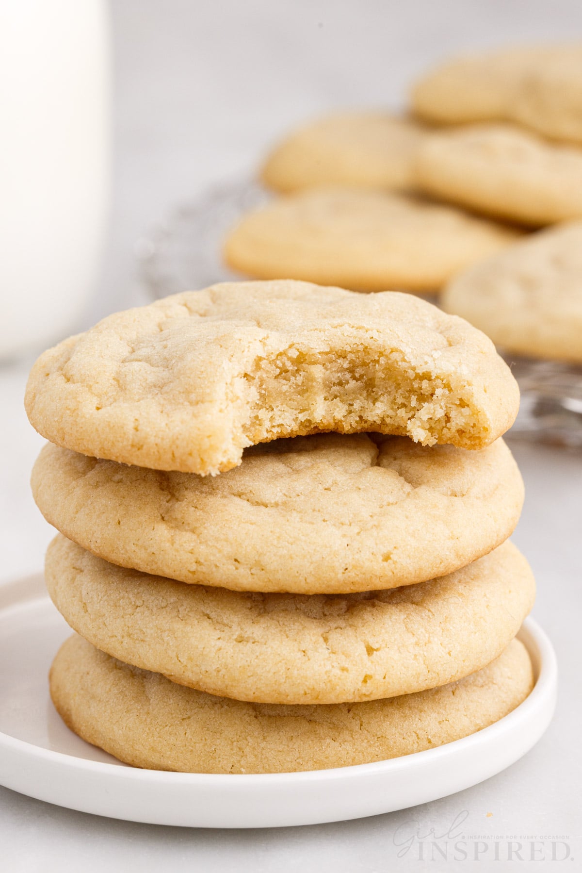 four soft sugar cookies stacked on each other with a bite out of the top one
