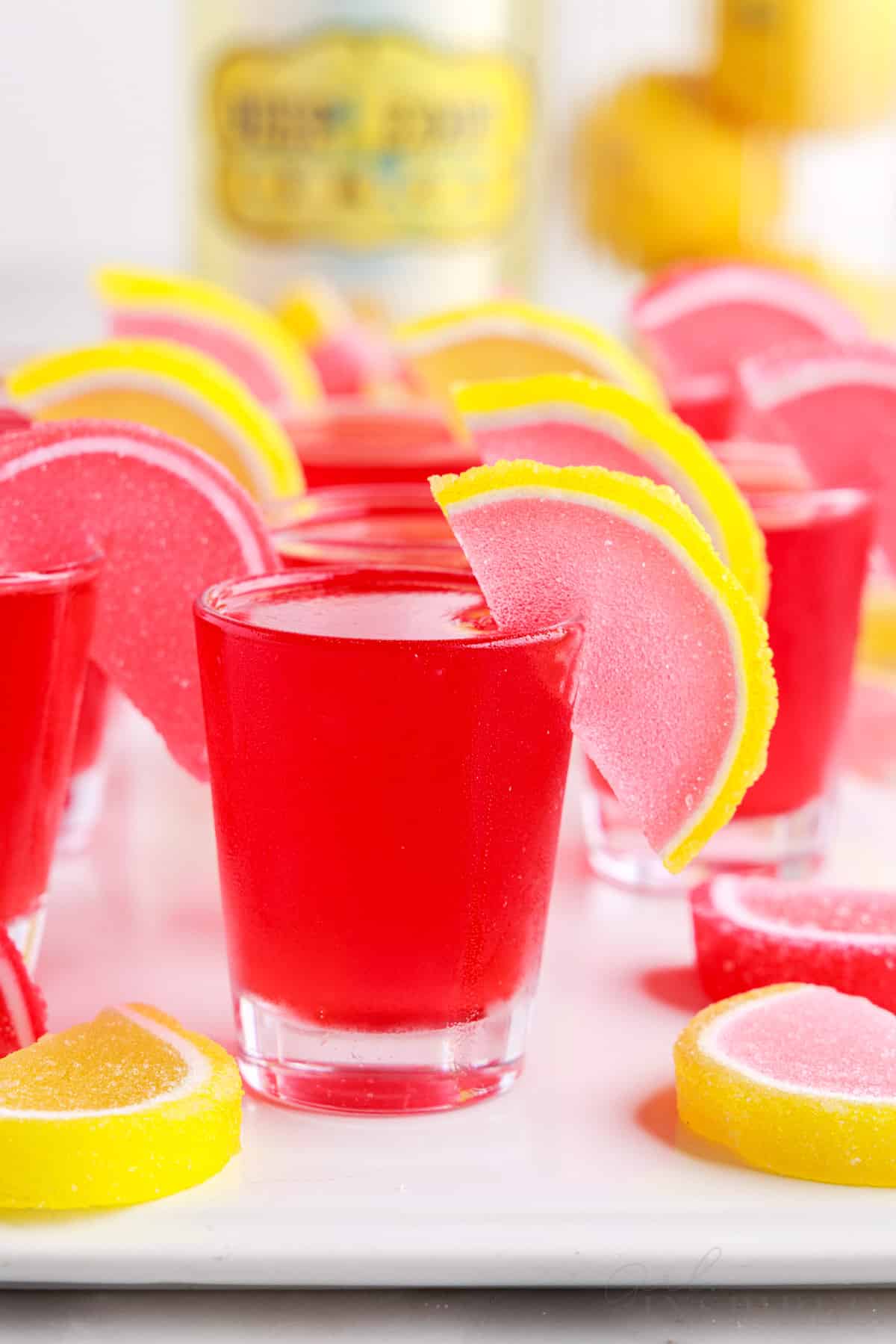 pink lemonade jello shots with candies hanging on the glass for garnish