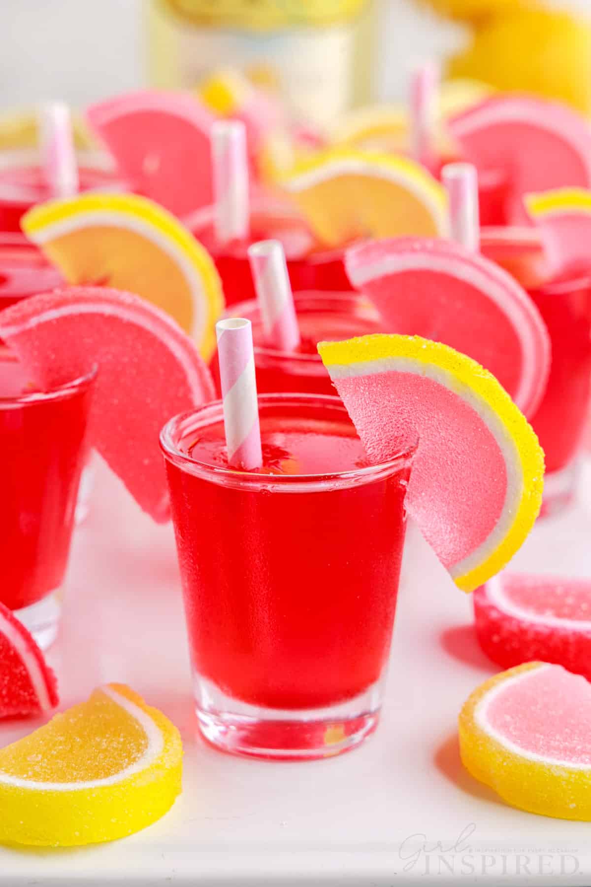 strawberry pink lemonade jello shots with paper straws in them