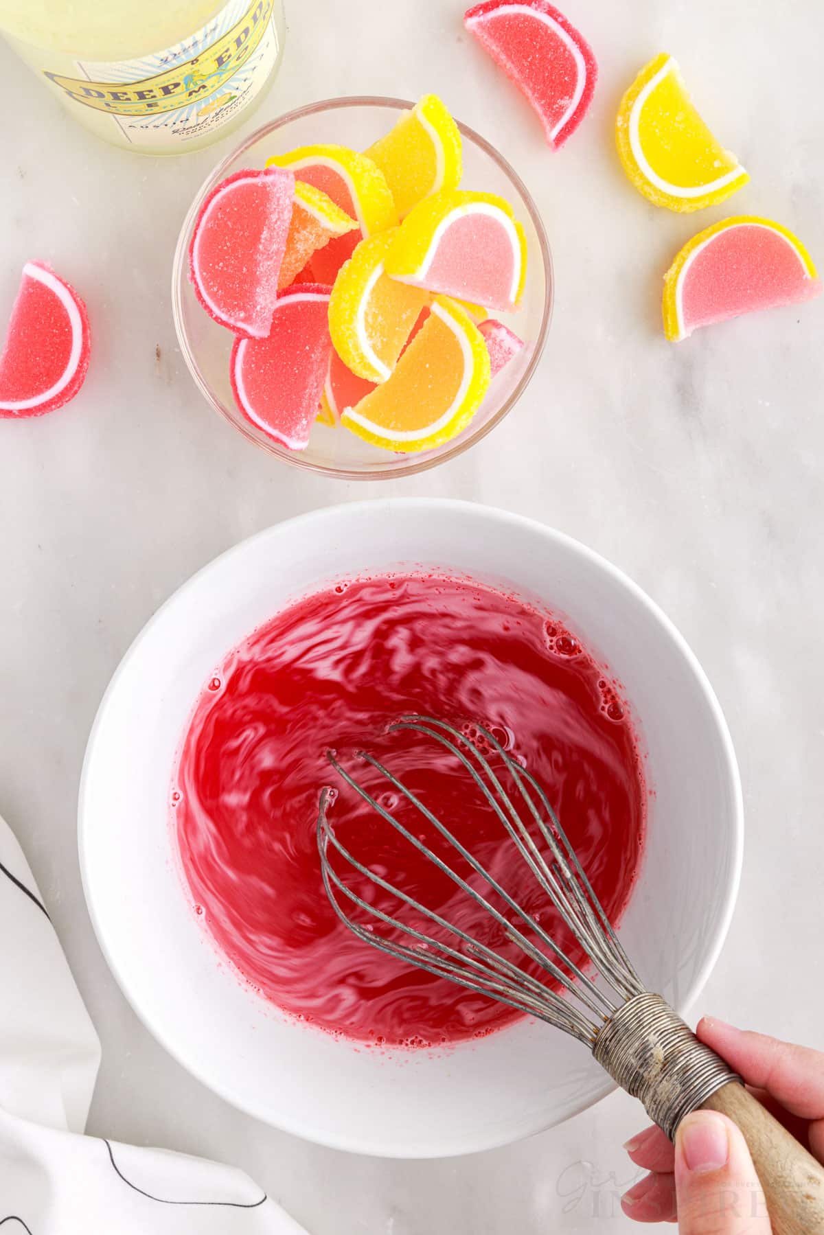 Whisking together the jello and water, lemon slice gummies in a bowl.