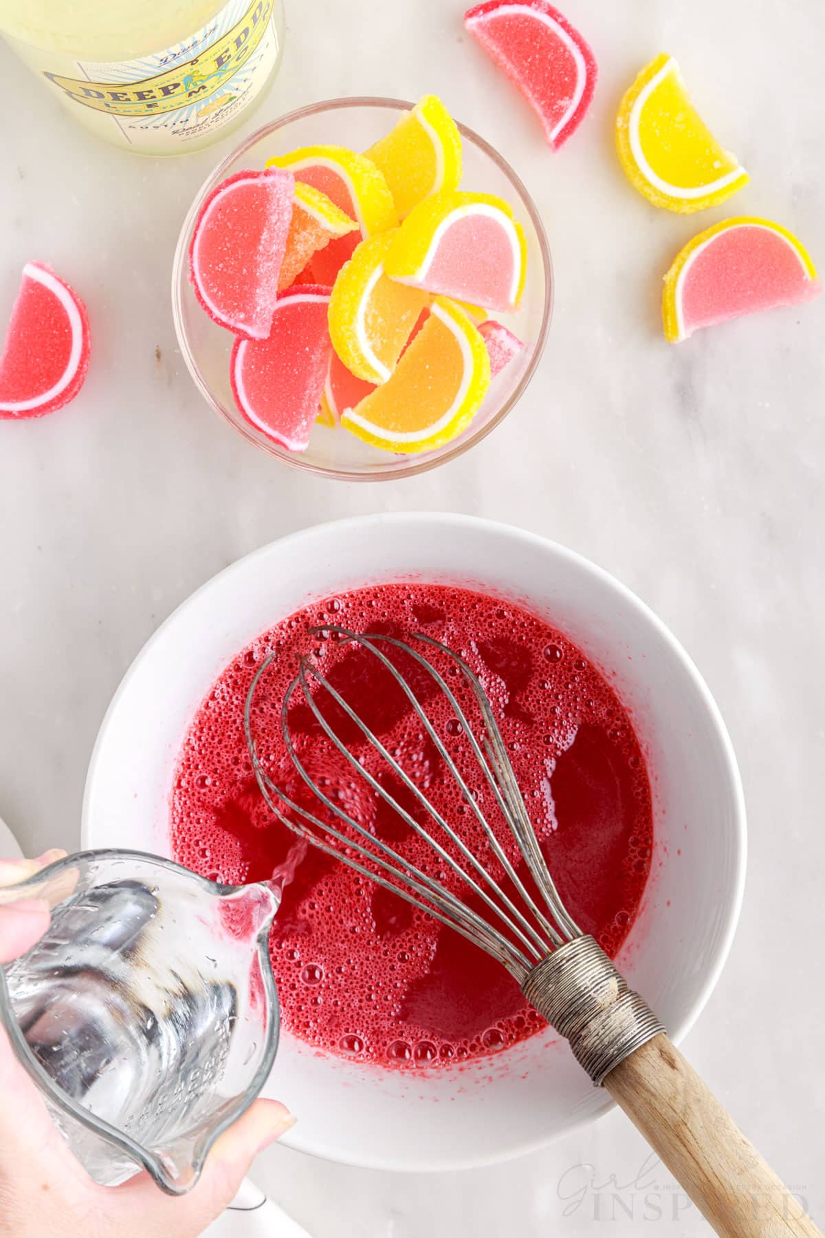 Pouring in cold water to the stawberry jello.