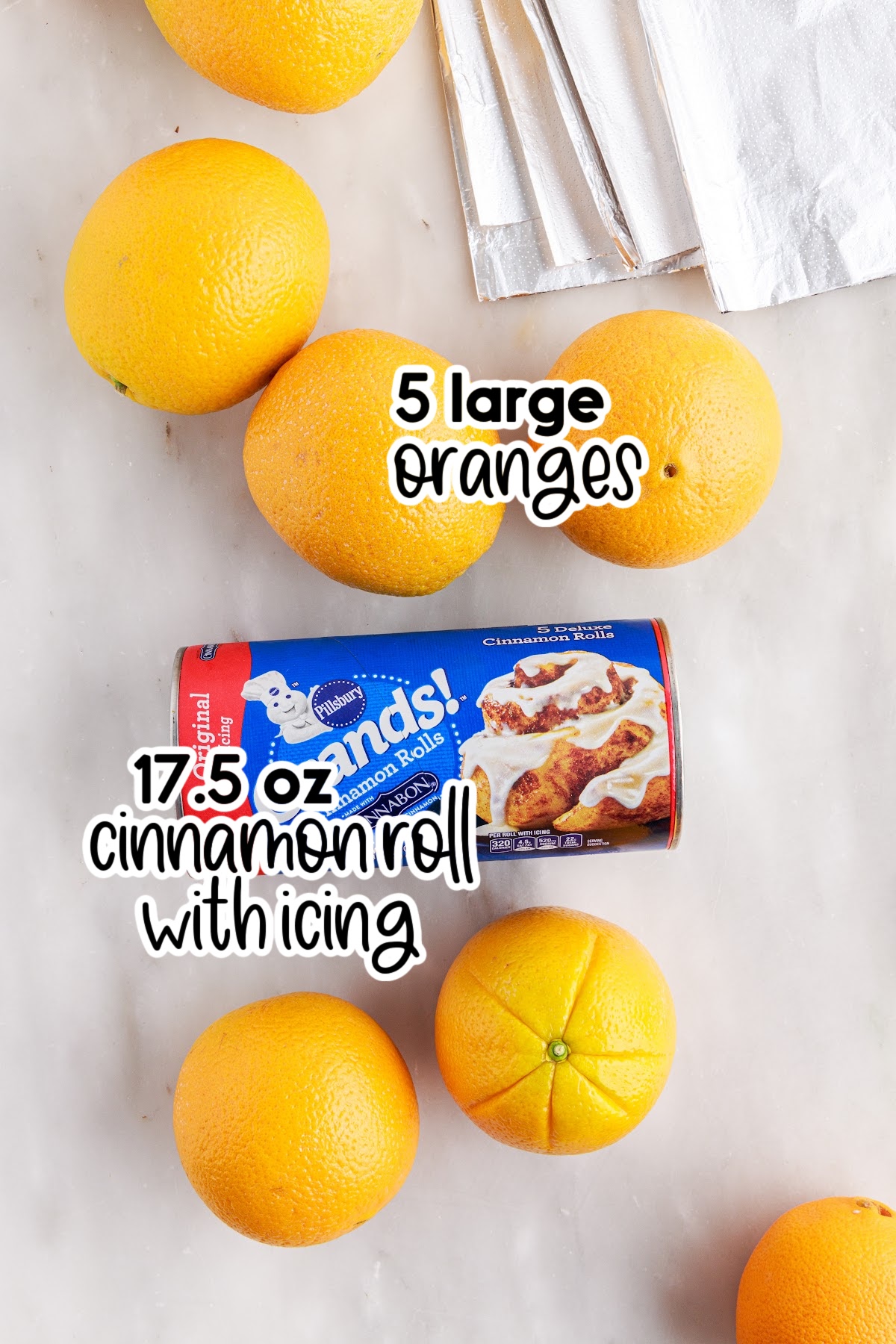 Individual ingredients for campfire cinnamon rolls - oranges and package of cinnamon rolls - with text labels.