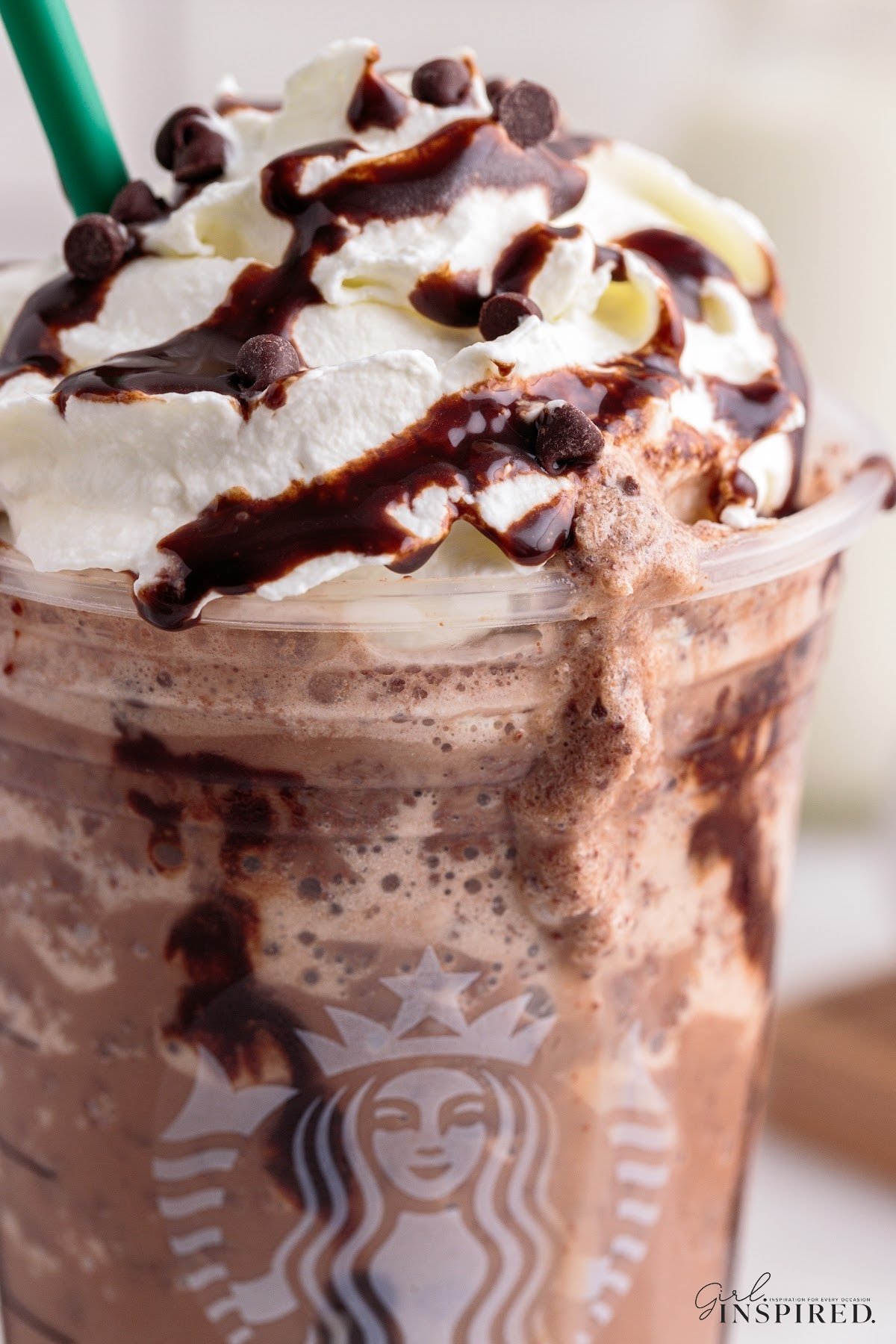 Close up of chocolate drizzle, chocolate chips, and whipped cream dripping off of Starbucks cup full of double chocolate chip frappuccino.