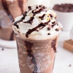 Starbucks cup of double chocolate chip frappuccino topped with whipped cream, chocolate drizzle, and mini chocolate chips.