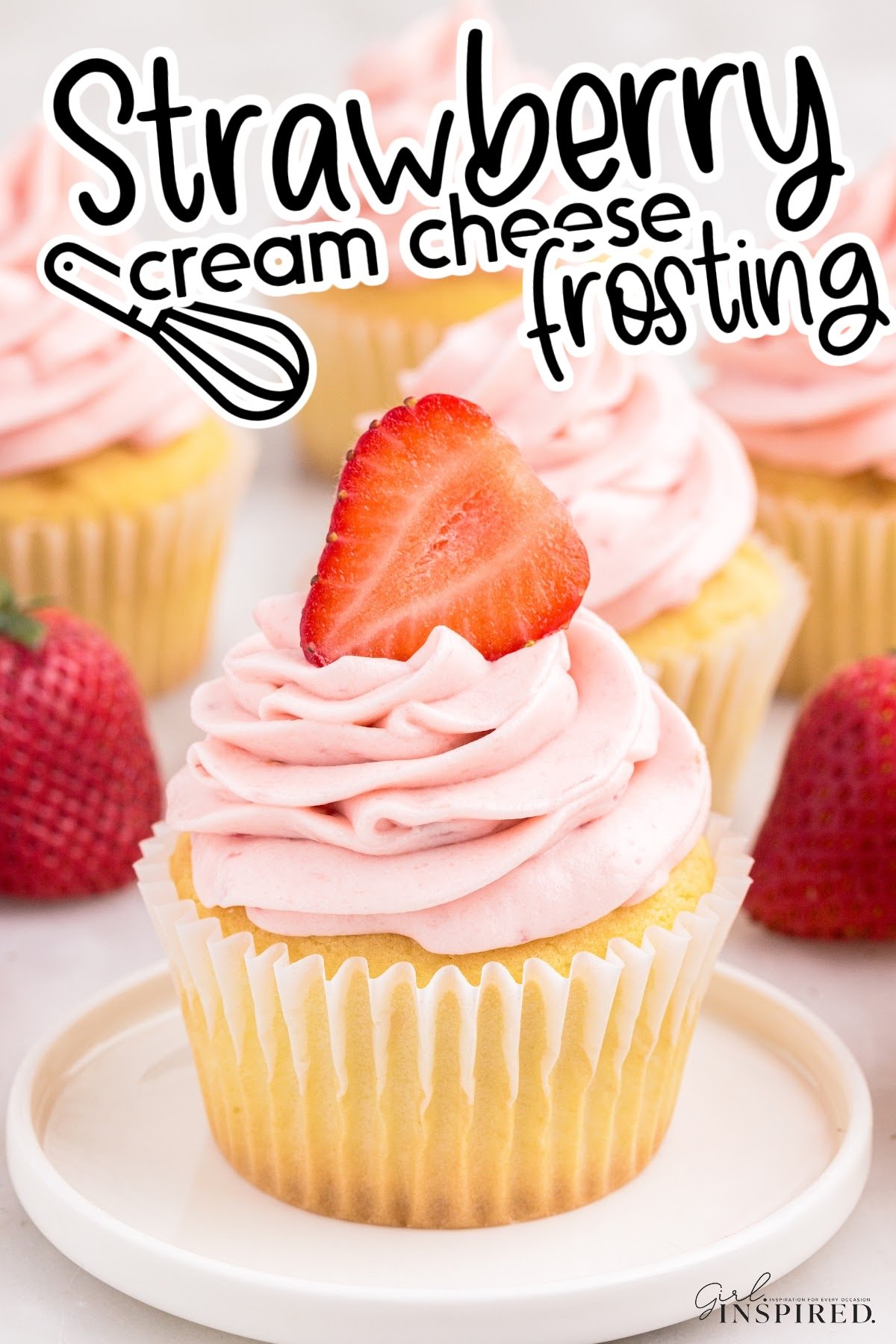 Yellow cupcake on small plate topped with strawberry cream cheese frosting and a half strawberry, with text overlay "Strawberry cream cheese frosting."