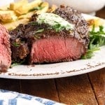 close of a filet mignon cut open on a plate next to fries