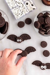 one mini oreo cookie top being pressed into two oreo halves for the bat
