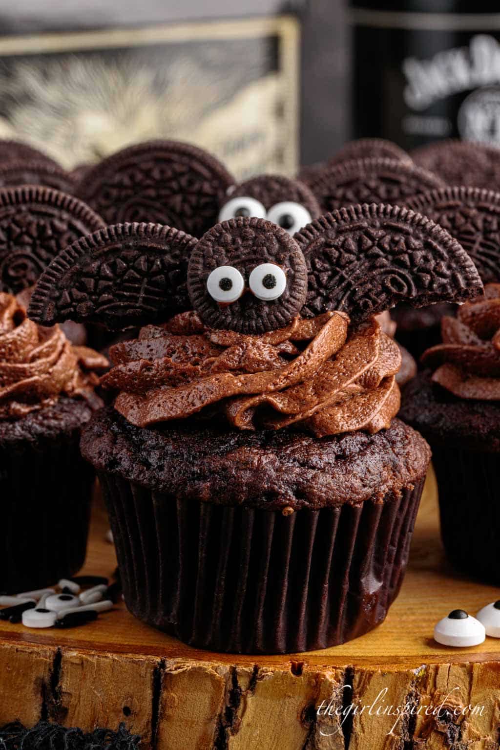 close up of a bat cupcake in front of other bat cupcakes with edible eyes around it