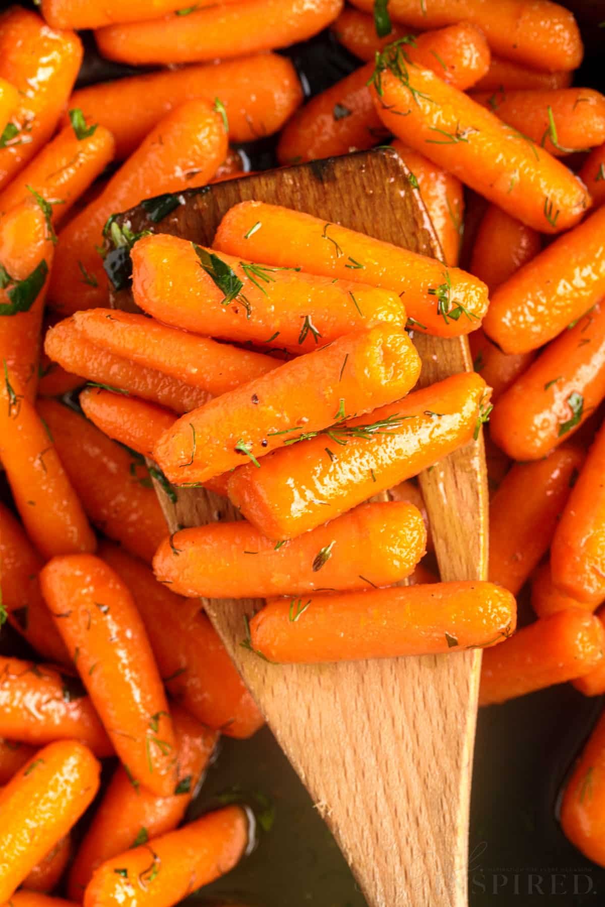 wooden spatula holding brown sugar honey glazed carrots