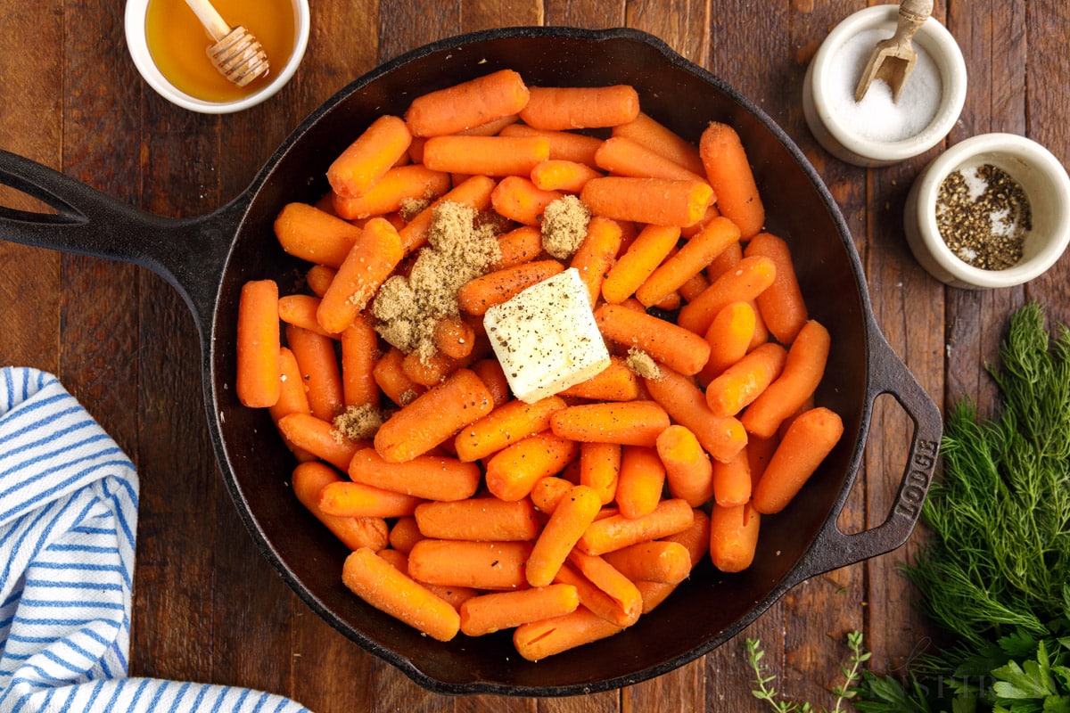 baby carrots in skillet topped with brown sugar and a pad of butter