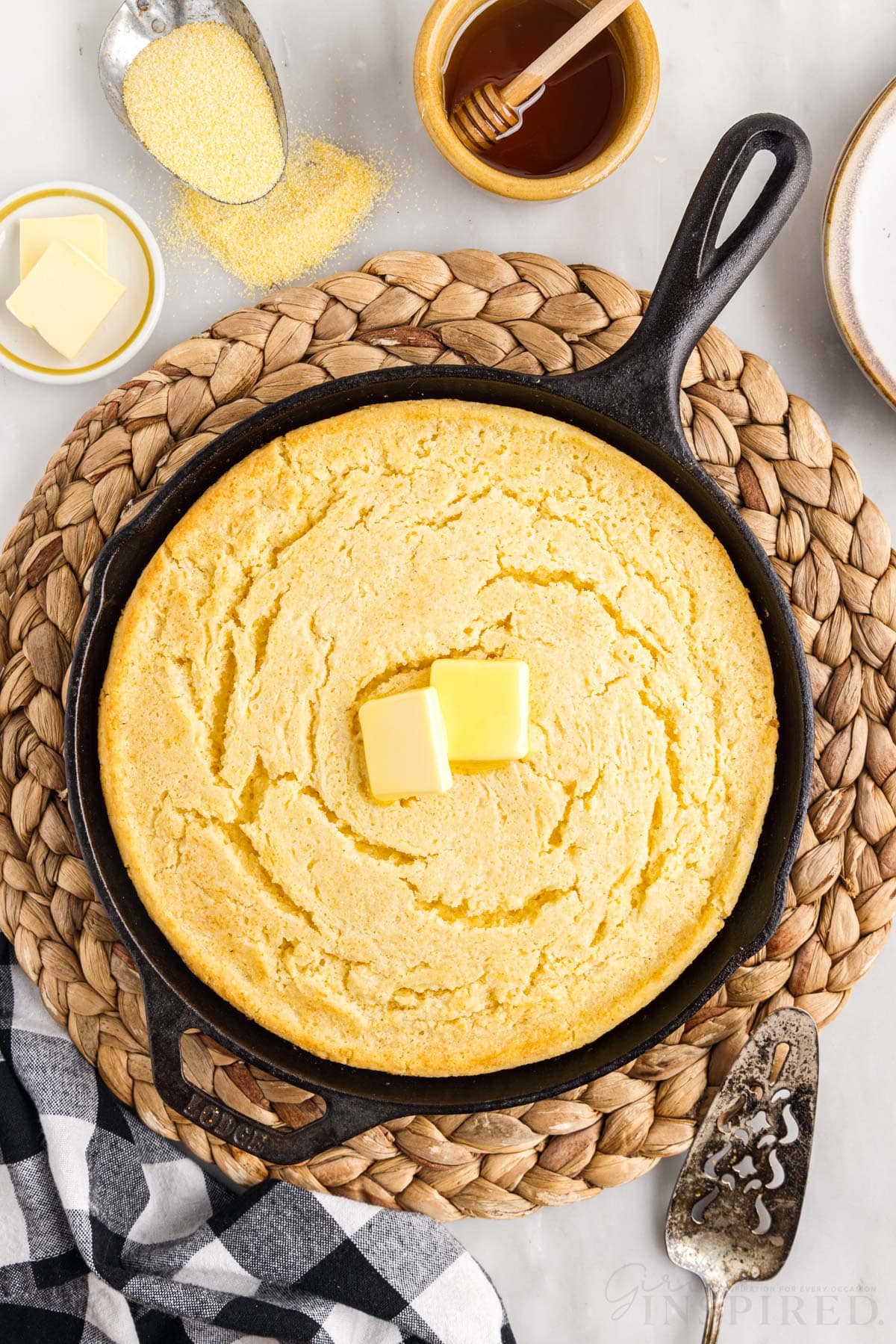 buttermilk cornbread in a skillet topped with slices of butter