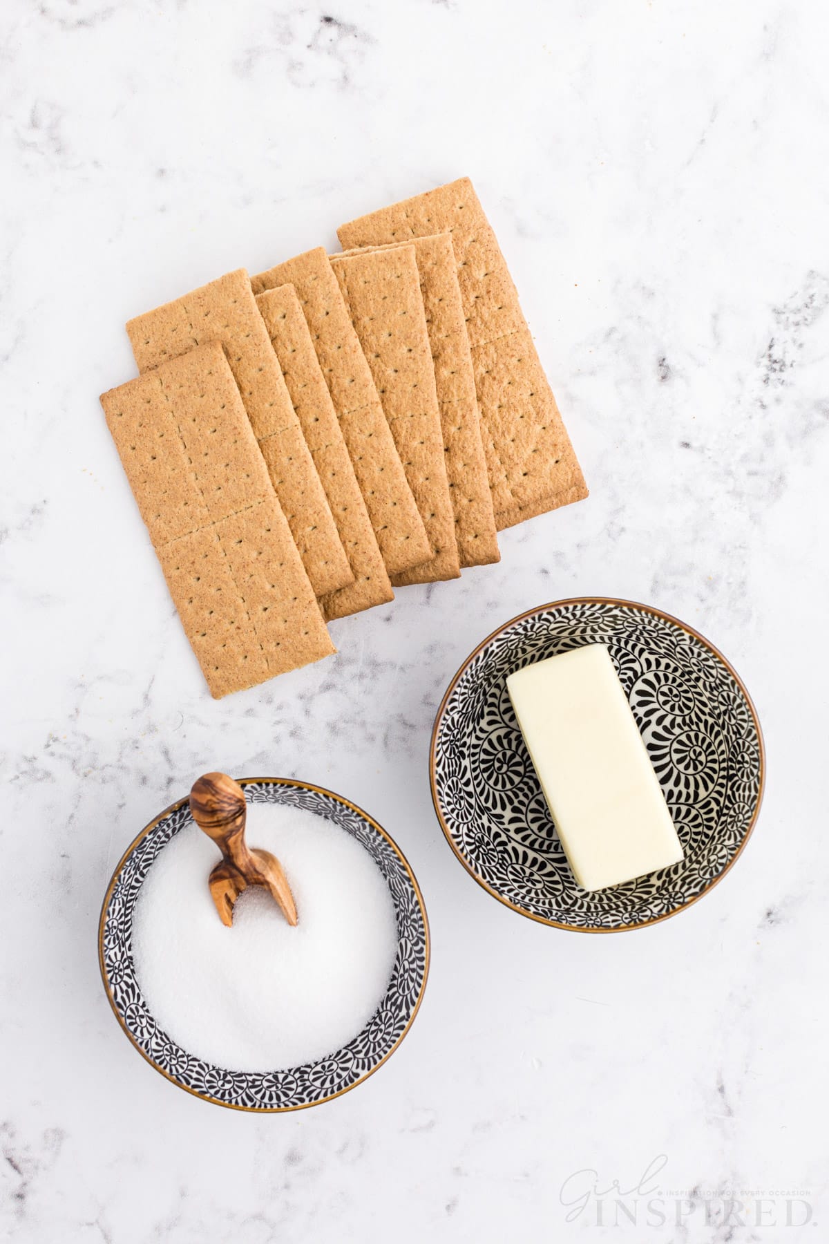 Individual ingredients for graham cracker crust: sugar, butter, and graham crackers.