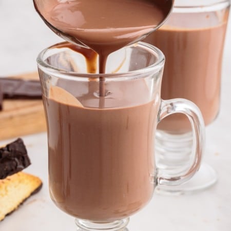 italian hot chocolate being poured into a glass with a ladle