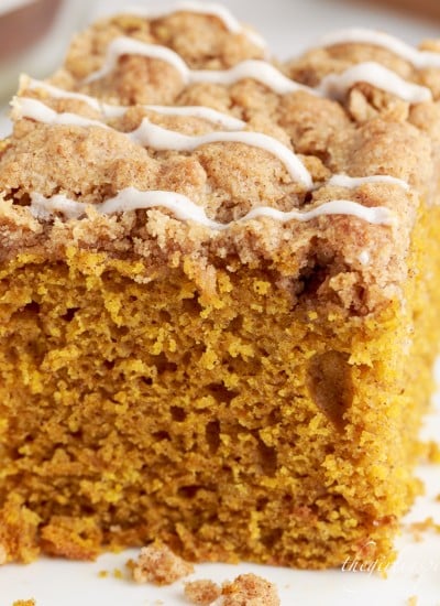 close up of a slice of pumpkin streusel coffee cake drizzled with glaze on a plate