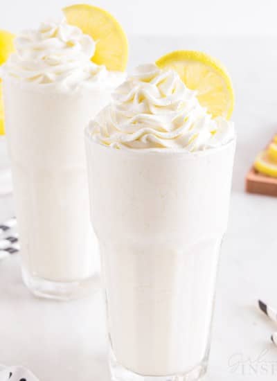 two whipped lemonades with whipped cream and a lemon slice on top.
