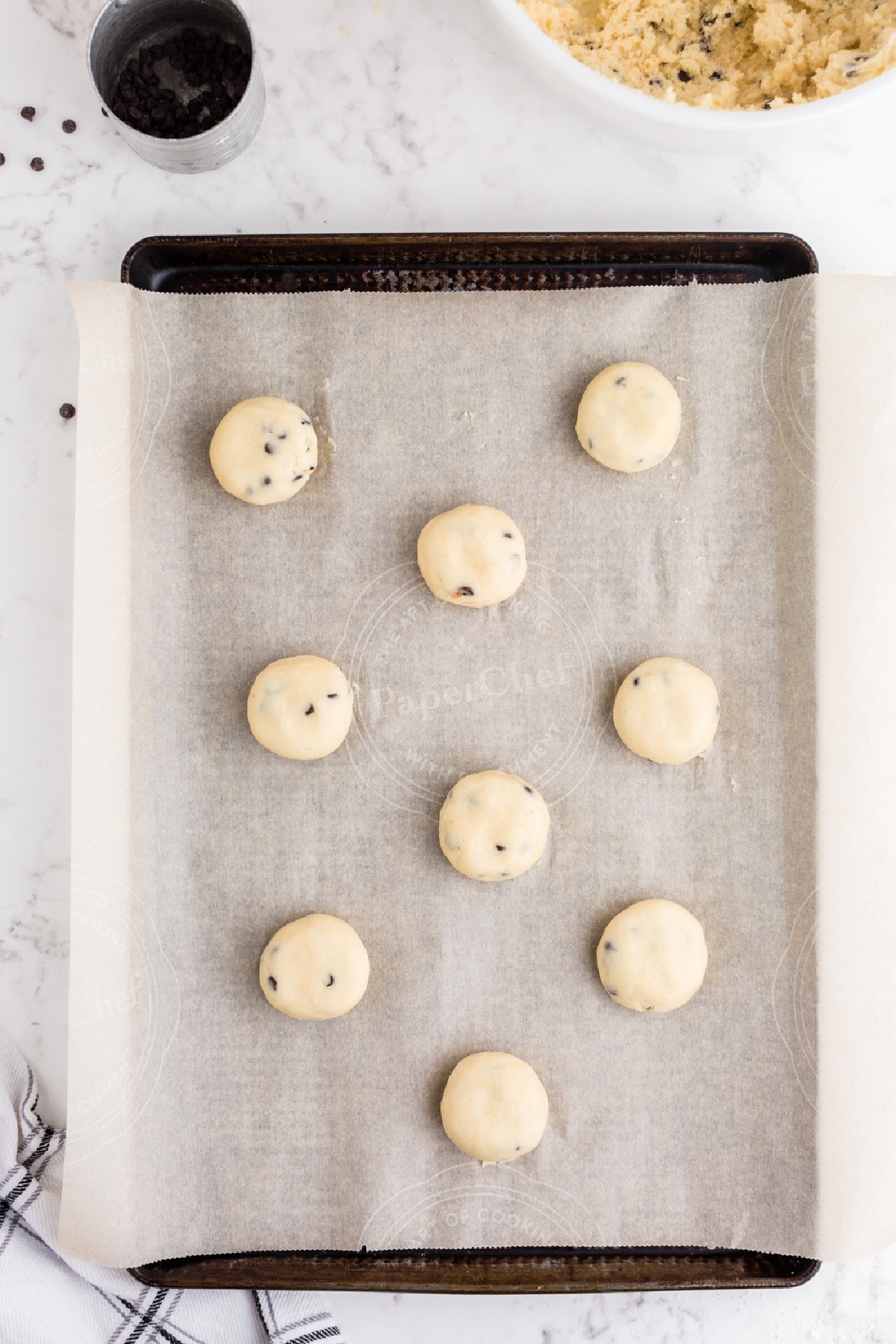 Sheet pan of slightly flattened balls of cookie dough.