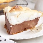 chocolate meringue pie slice on a white plate with a fork