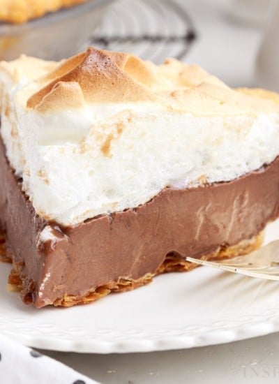 chocolate meringue pie slice on a white plate with a fork