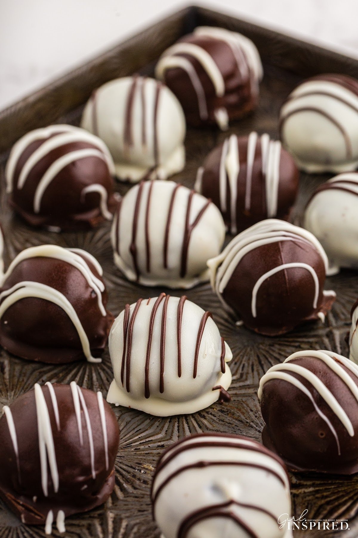 Variety of white and milk chocolate coated Oreo cookie balls on a baking sheet.