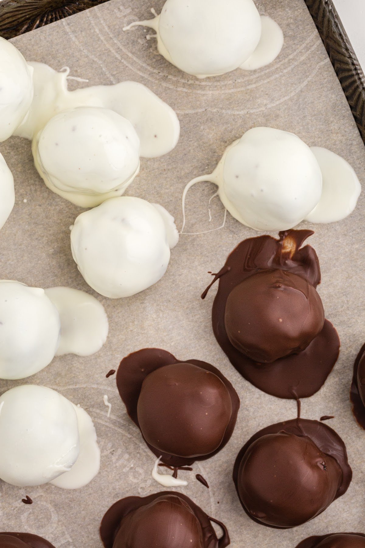 Oreo balls coated in dark and white chocolate on parchment lined baking sheet.