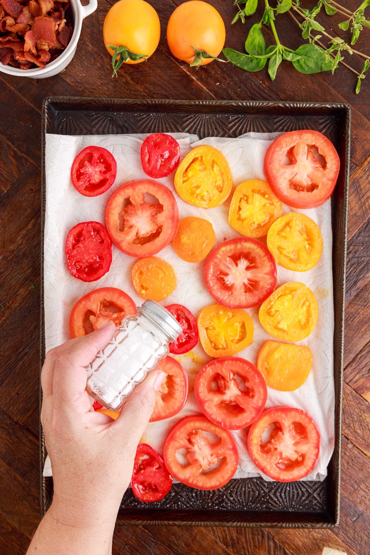 Shaking salt shaker over the tomato slices spread out over paper towels in sheet pan.