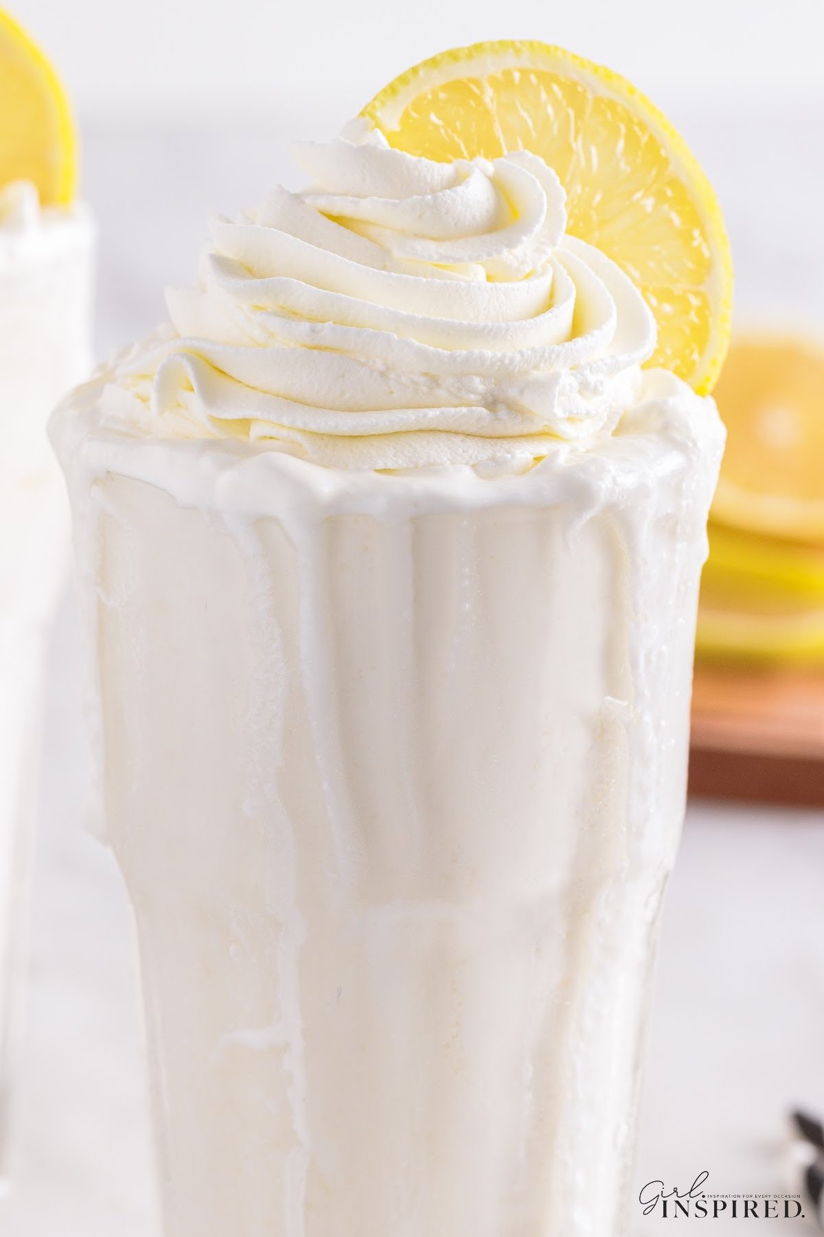 Whipped lemonade in serving glass with drips of whipped cream spilling over sides of glass.