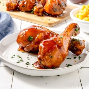 close up of two air fried bbq chicken legs on a small white plate