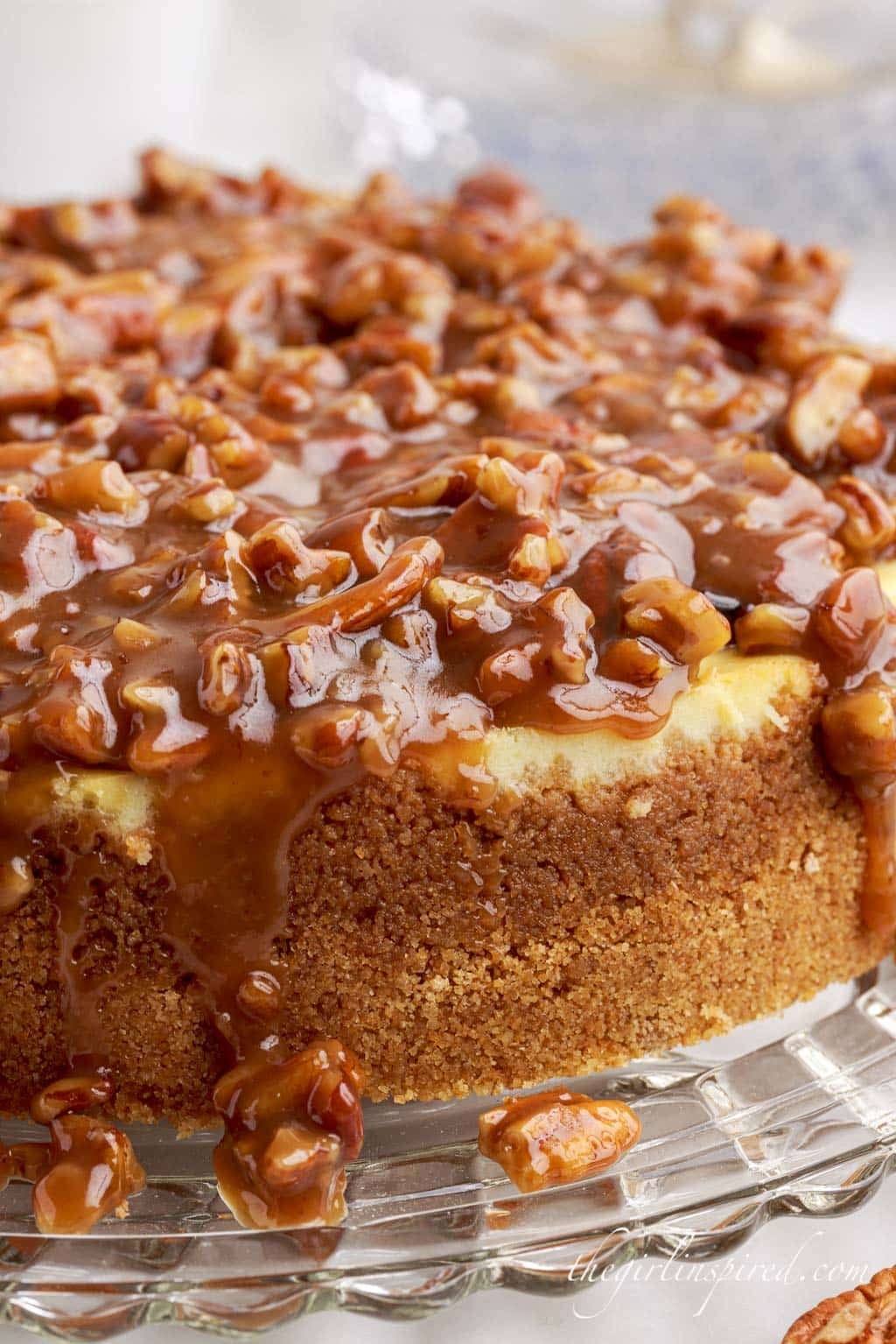 front view of caramel pecan pie cheesecake on a glass dish