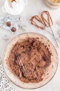 chocolate crackle cookie dough in mixing bowl covered with plastic wrap