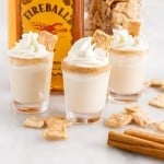 three cinnamon toast crunch shots with cinnamon toast crunch and fireball whiskey in the background