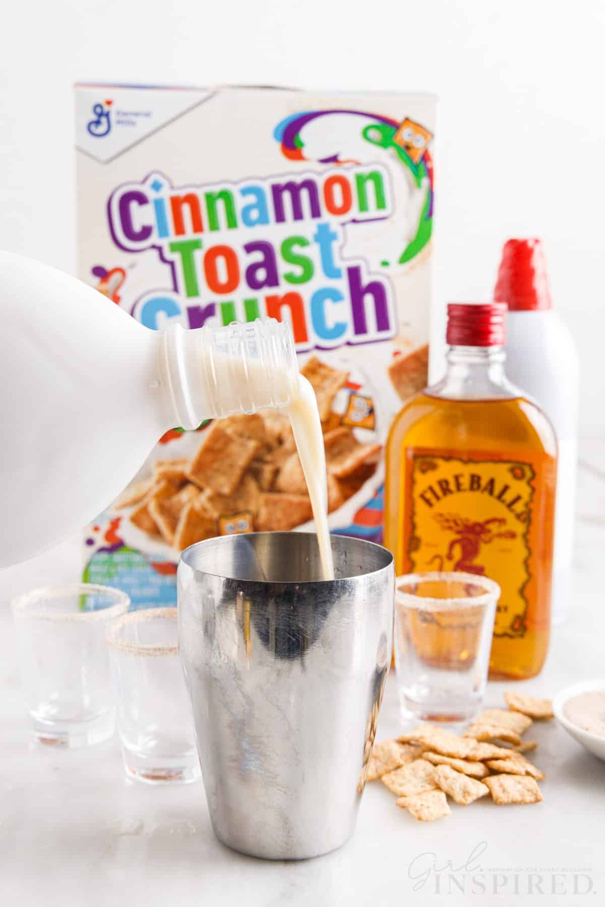 RumChata poured into a shaker, cinnamon toast crunch cereal box in the background