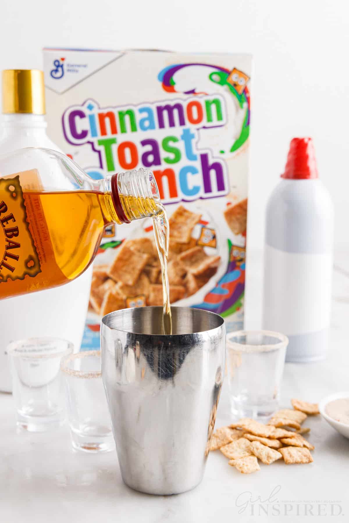 Fireball whiskey poured into a shaker cinnamon toast crunch in the background.