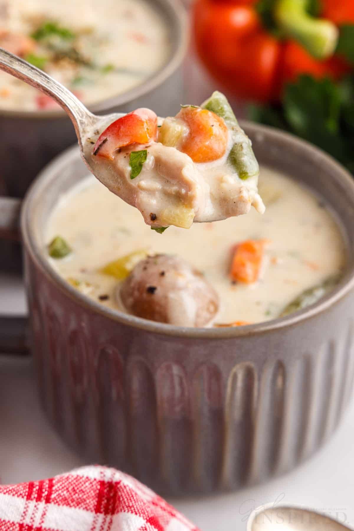 spoon of creamy chicken stew over a soup cup