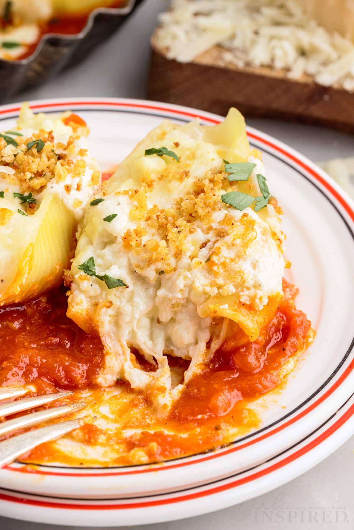 close up of giant cheese stuffed shells olive garden on a plate with a bite taken from one